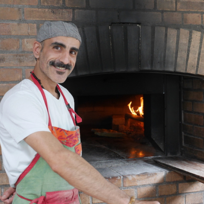 Furat vor seinem selbstgebauten Holzbackofen. Foto: Elisabeth Fischer